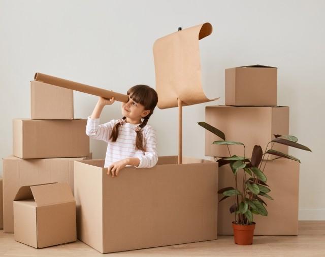 A little girl plays make-believe with corrugated boxes